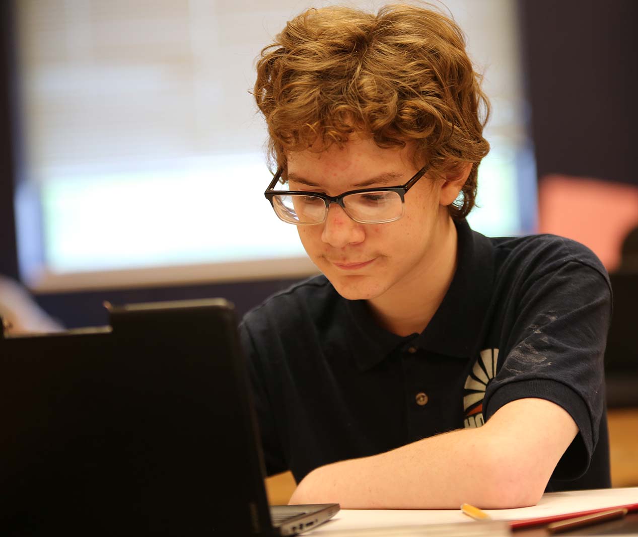 Student working on a notebook in a classroom.